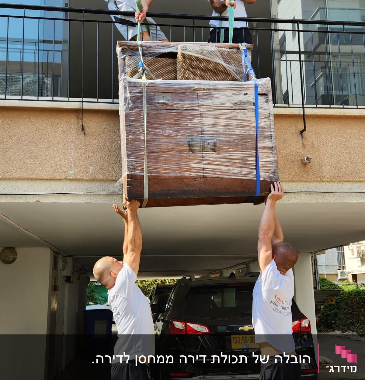 אנשים מורידים רהיט גדול בעזרת רצועות מהמרפסת